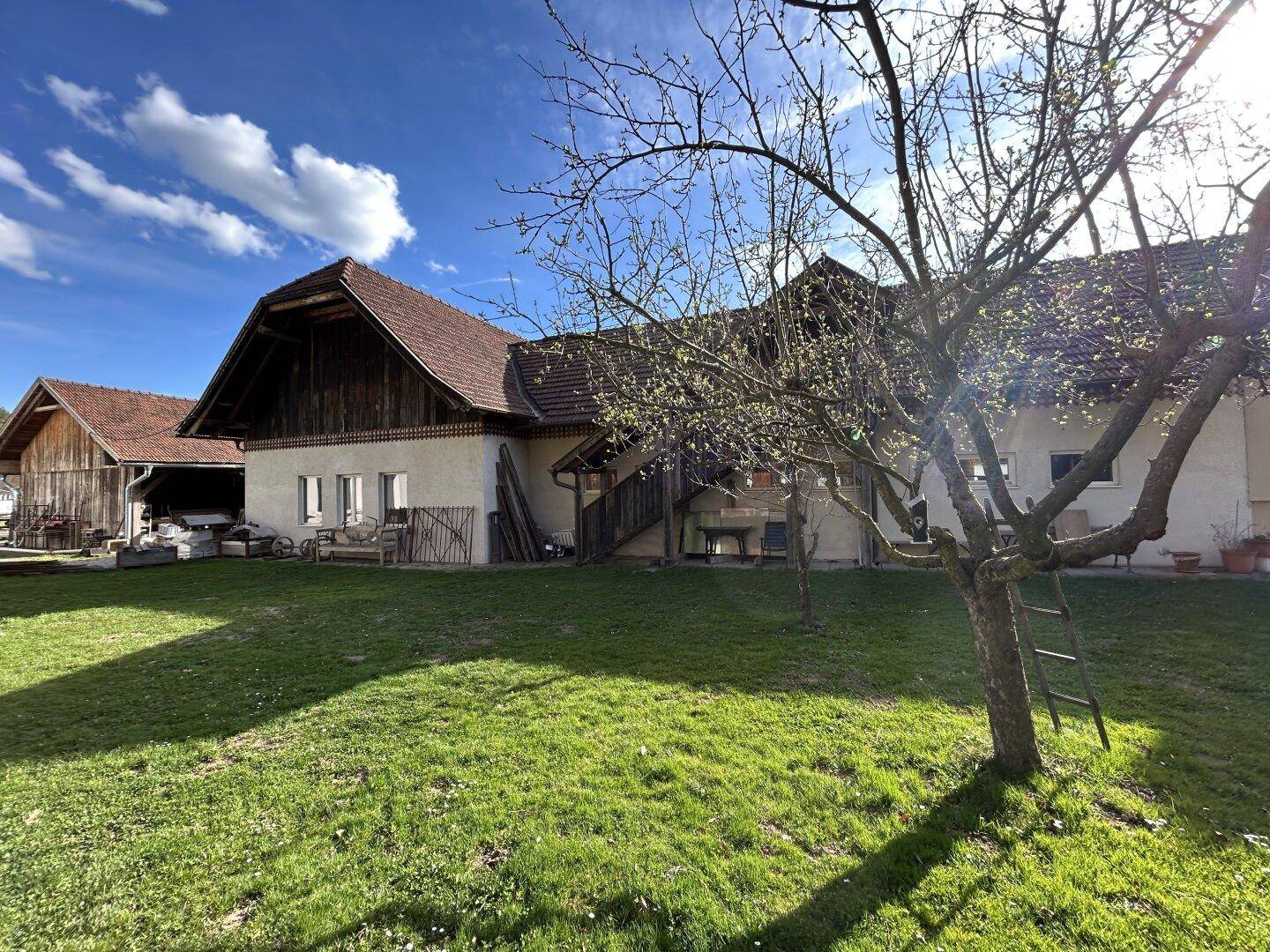 Großer Gartenbereich mit grüner Wiese und Bäumen, angrenzend an das traditionelle Gebäude.