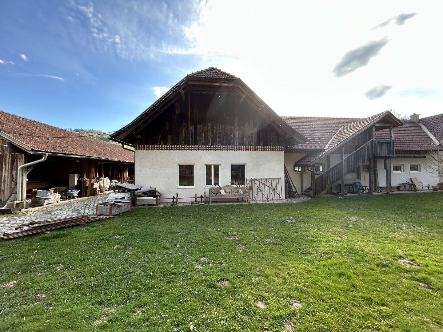 Weitläufiger Garten mit grüner Wiese und Blick auf das traditionelle Gebäude mit Holzelementen.