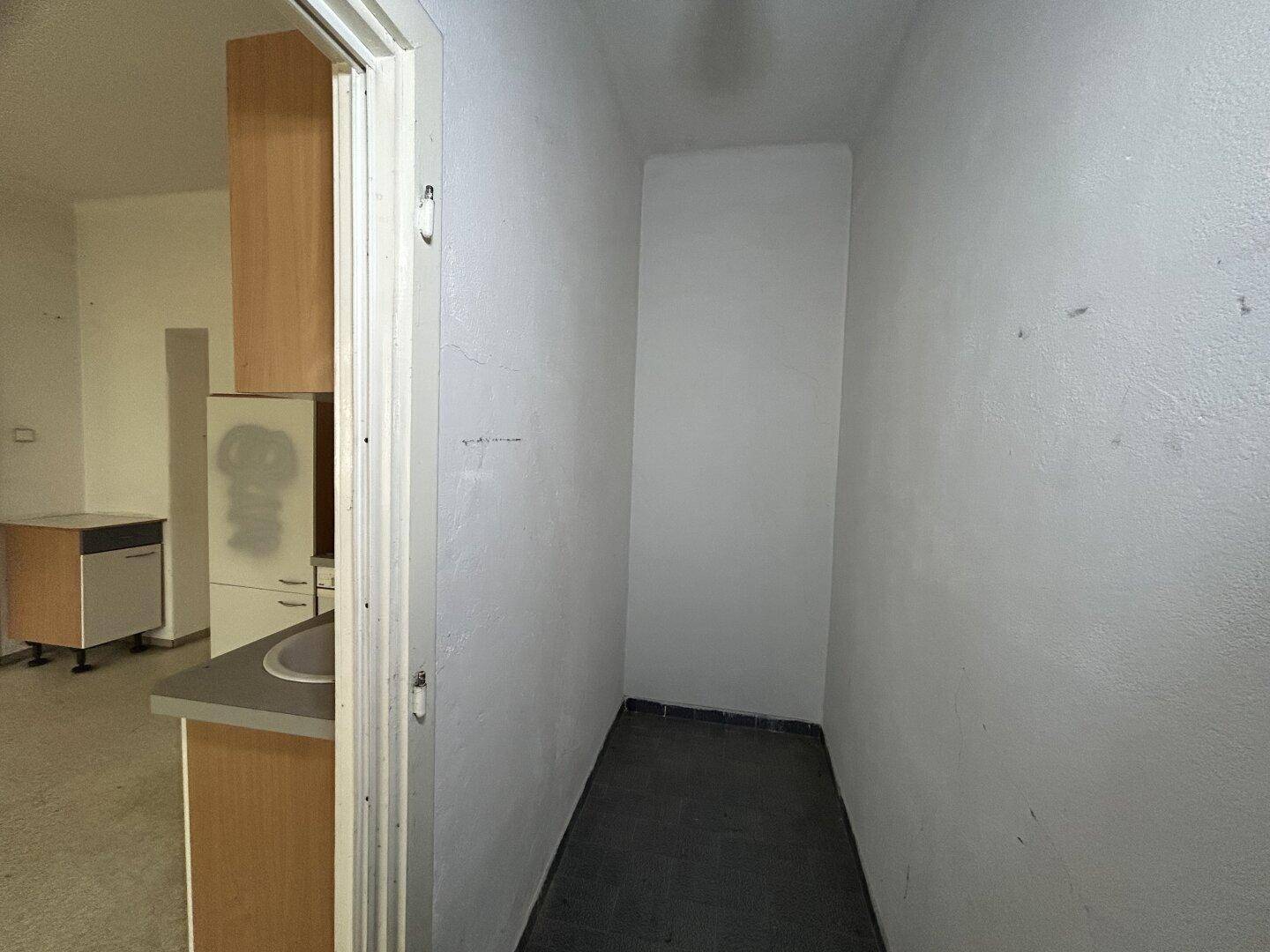Kleiner Abstellraum mit dunklem Boden und weißen Wänden, angrenzend an die Küche.