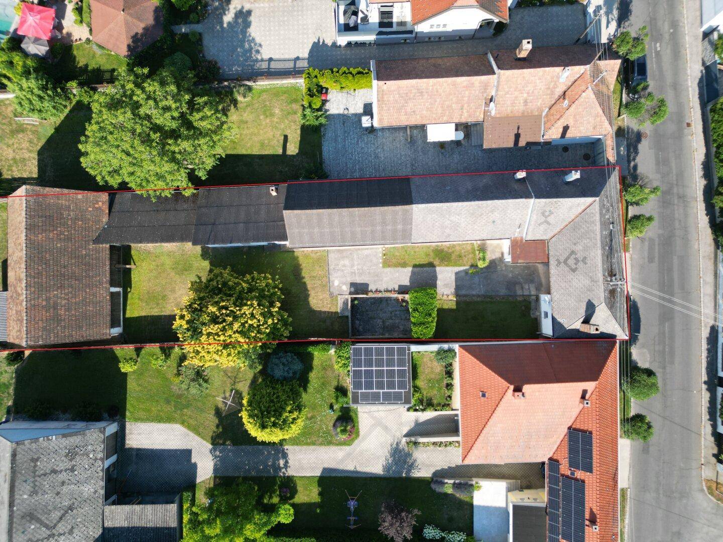 Luftaufnahme eines Anwesens mit Gebäuden, Innenhof und Photovoltaikanlage auf dem Dach.