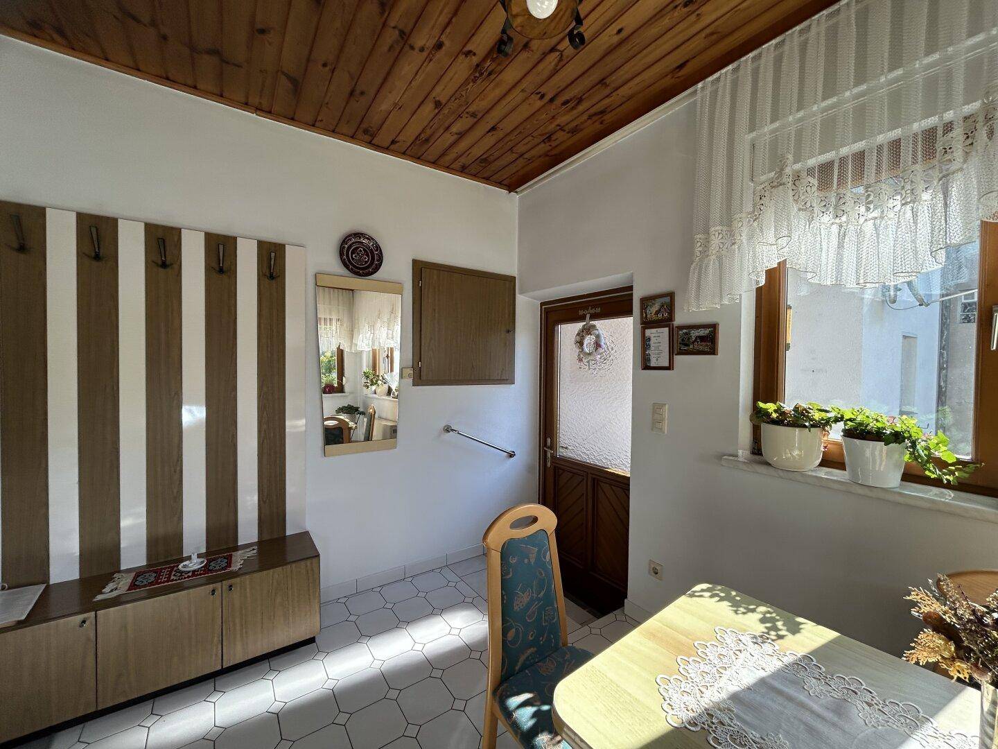 Heller Flur mit Garderobe, Spiegel und Holzdecke, führt zu weiteren Räumen.
