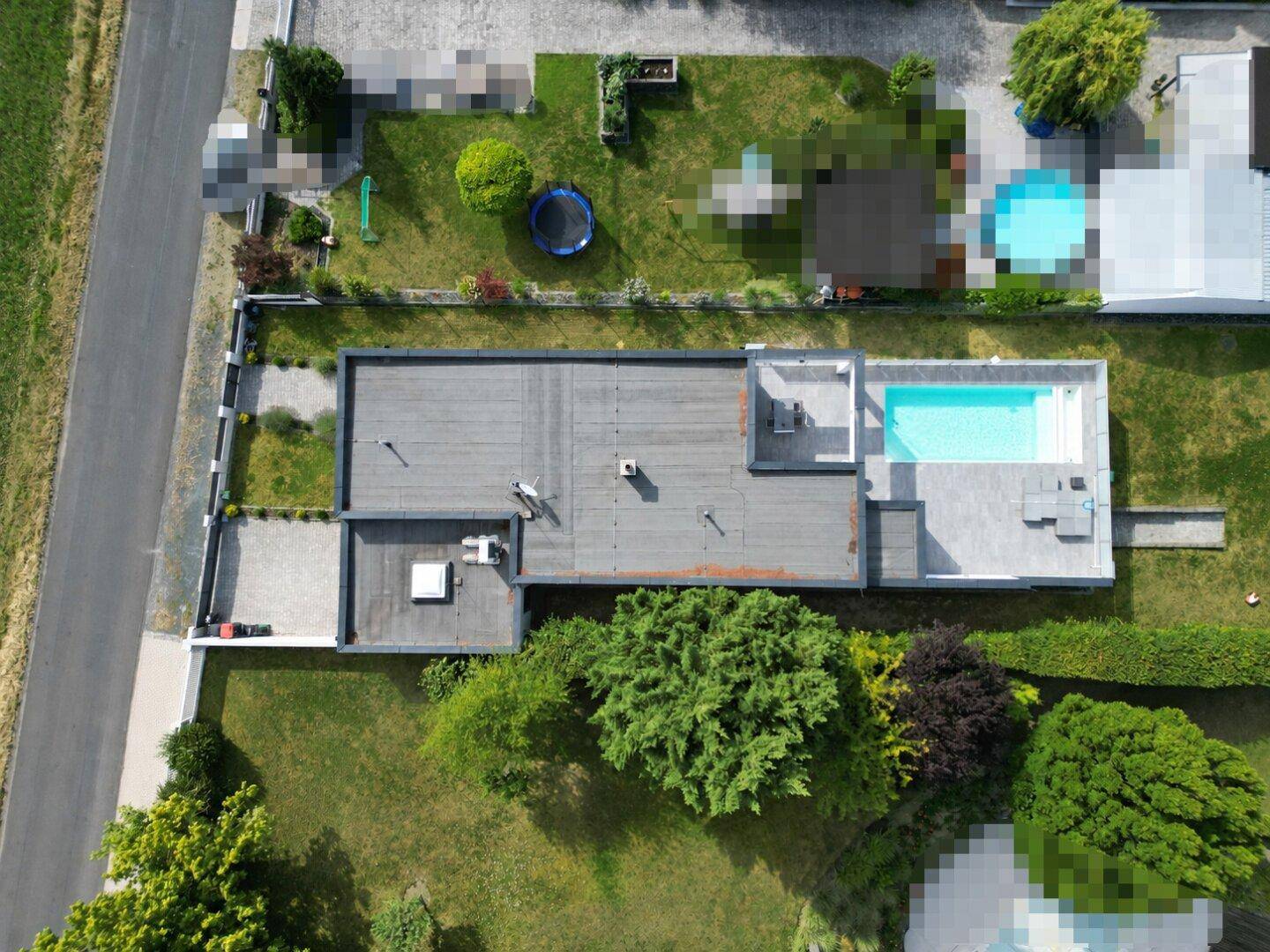 Luftaufnahme des Anwesens mit Flachdachhaus, Swimmingpool und weitläufigem Gartenbereich.