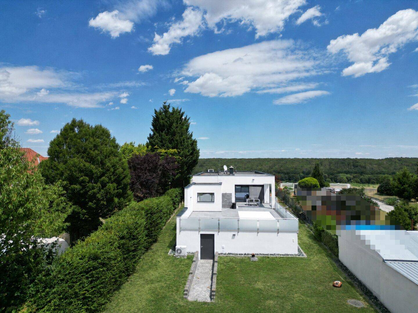 Hinterhof mit gepflegtem Rasen und Zugang zu einer modernen Terrasse mit Glasgeländer.