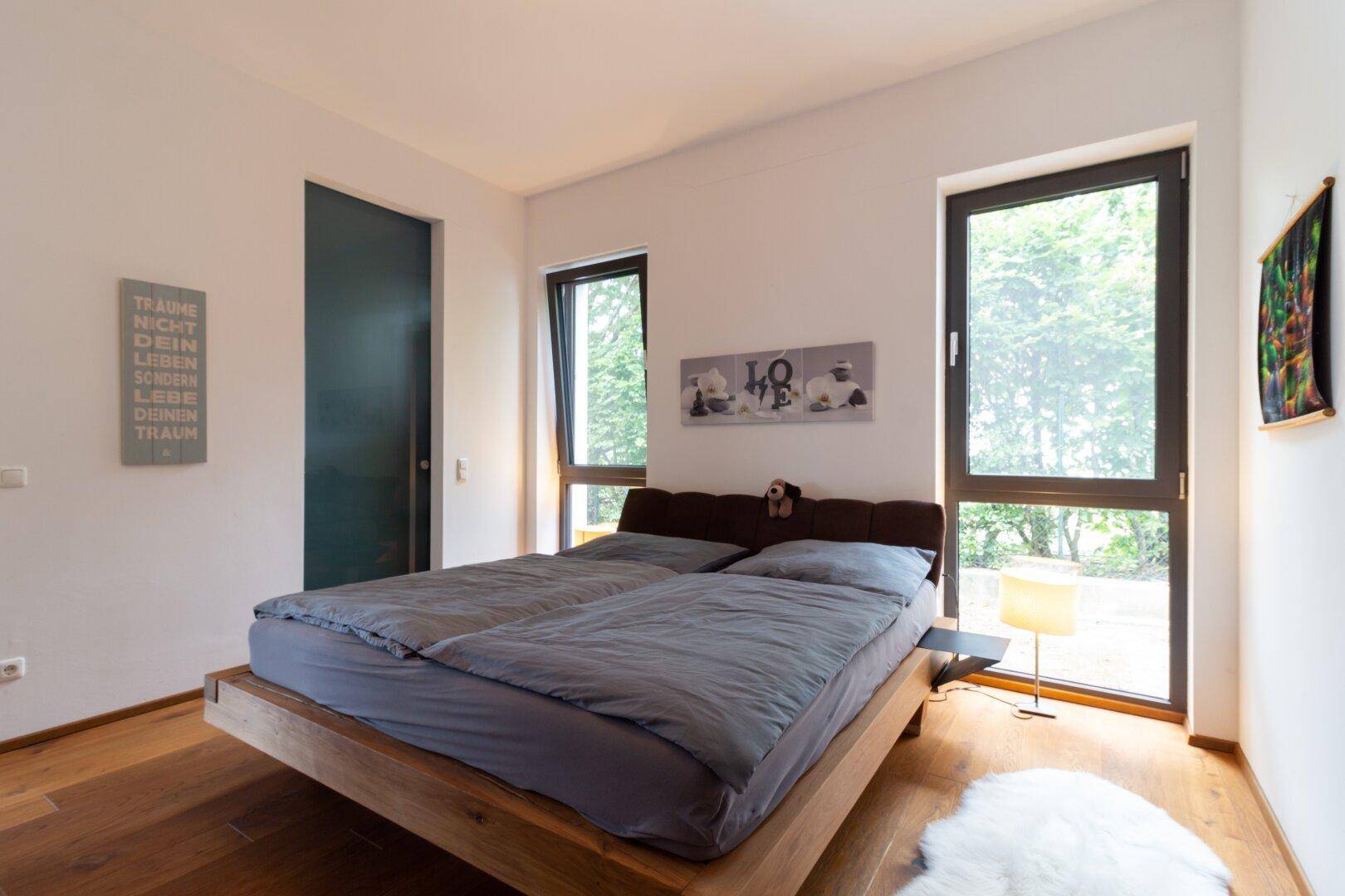 Geräumiges Schlafzimmer mit Holzboden, viel Tageslicht und Zugang zum Ankleidezimmer.