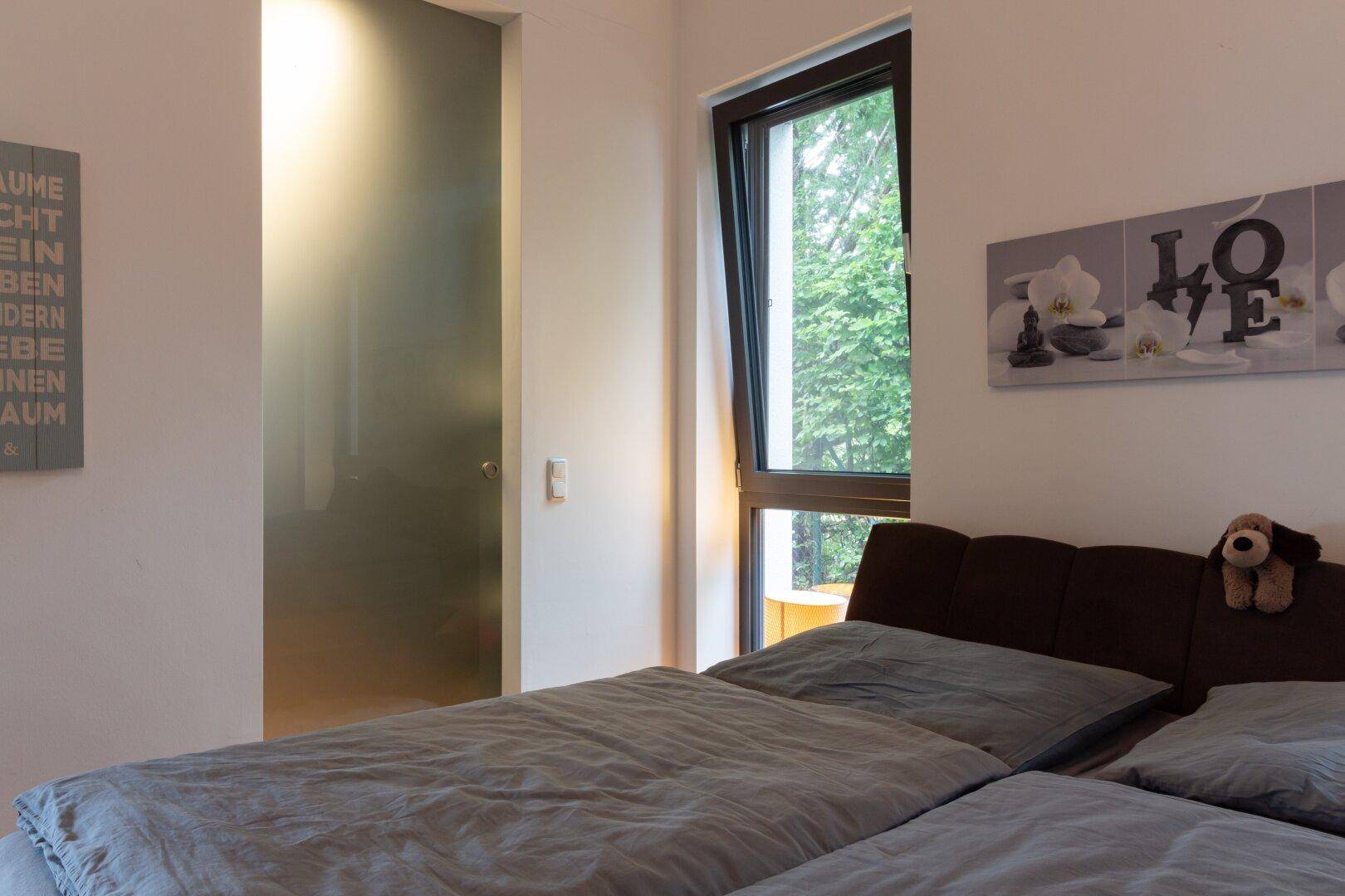 Schlafzimmer mit Holzboden und Blick auf die moderne Schiebetür zum Ankleidezimmer.