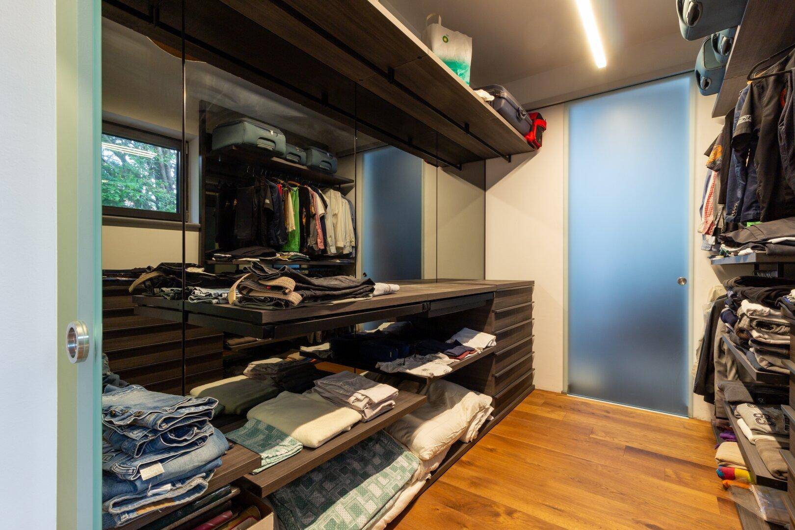 Begehbarer Kleiderschrank mit maßgefertigten Regalen, Schubladen und Spiegelflächen.