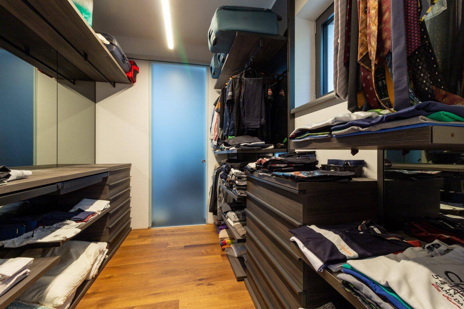 Gut organisierter begehbarer Kleiderschrank mit viel Stauraum und Holzboden.