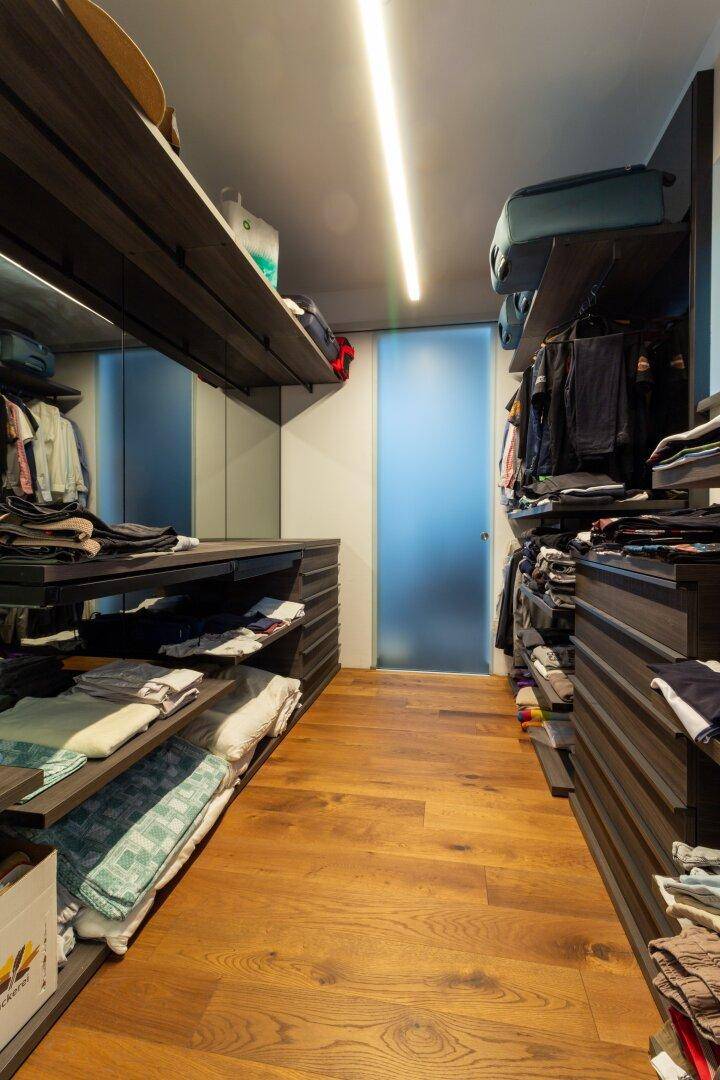 Geräumiger begehbarer Kleiderschrank mit Holzboden und vielseitigen Aufbewahrungslösungen.