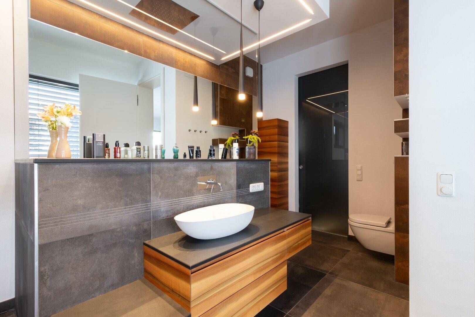 Modernes Badezimmer mit dunklen Fliesen, Holzwaschtisch und Aufsatzwaschbecken.
