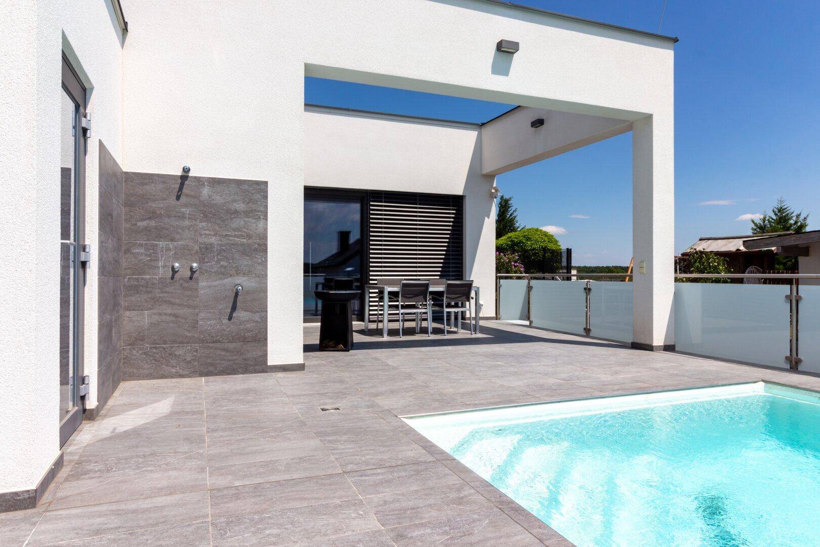 Geräumige Terrasse mit Pool, Essbereich und Außendusche, ideal für Entspannung im Freien.