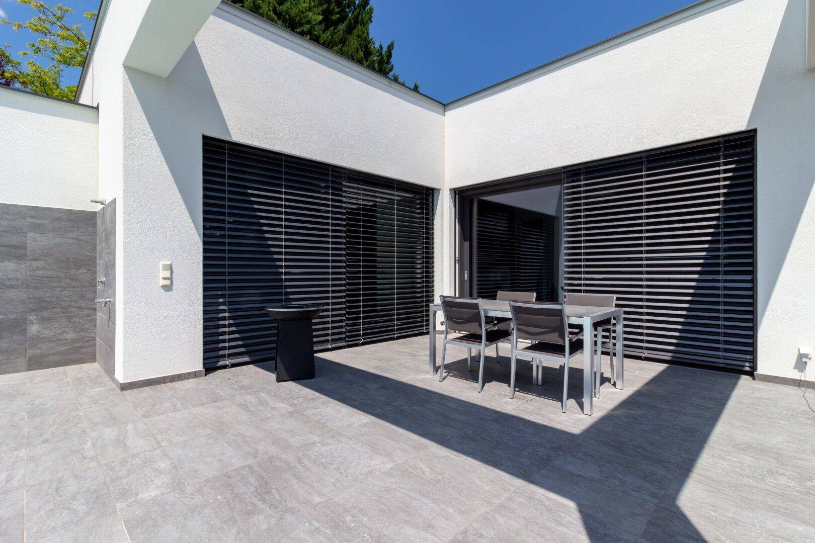 Überdachter Terrassenbereich mit modernem Esstisch und Stühlen, ideal für Mahlzeiten im Freien.
