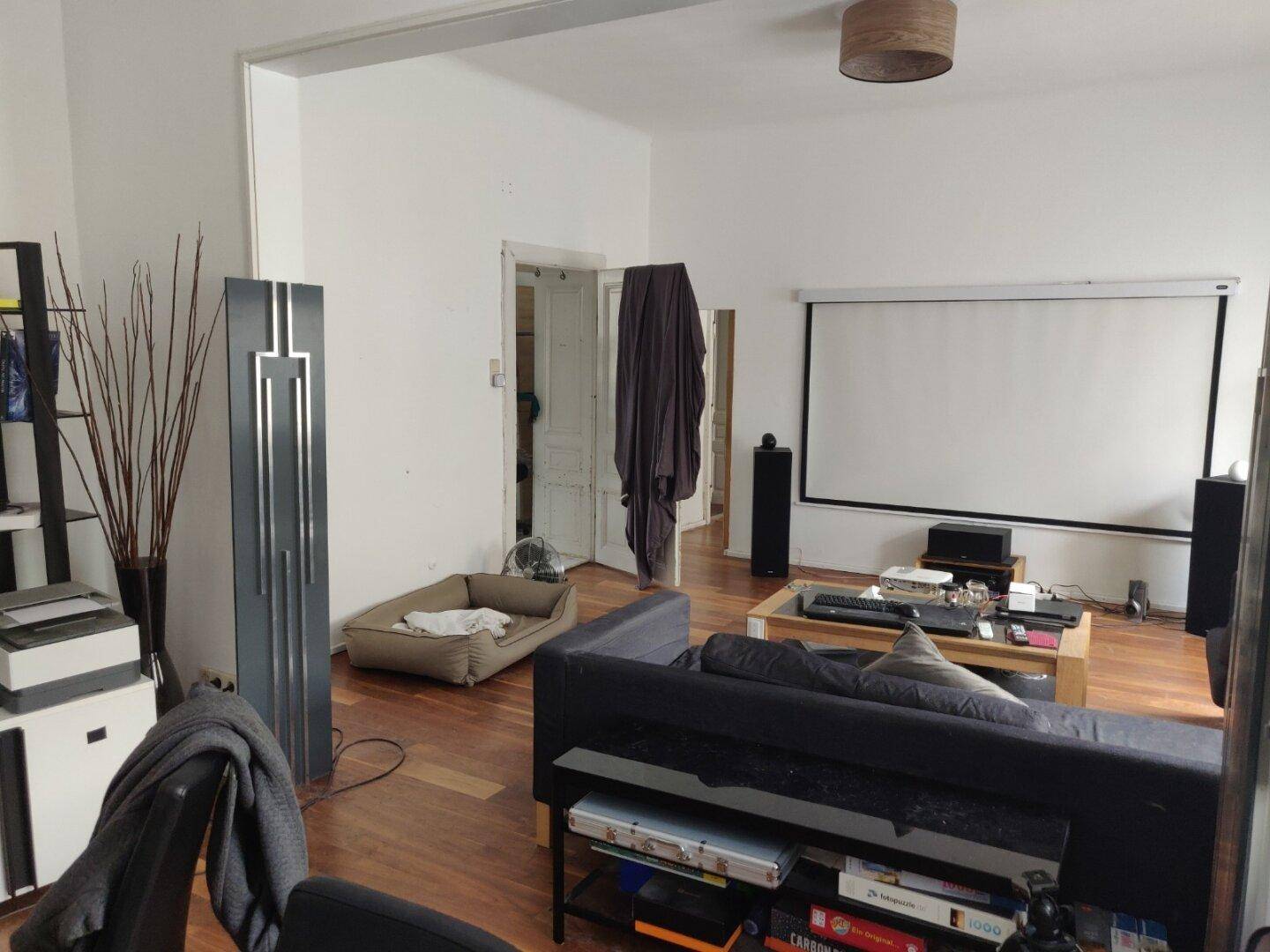 Großes Wohnzimmer mit Projektionsleinwand, Sofa und Holzboden.