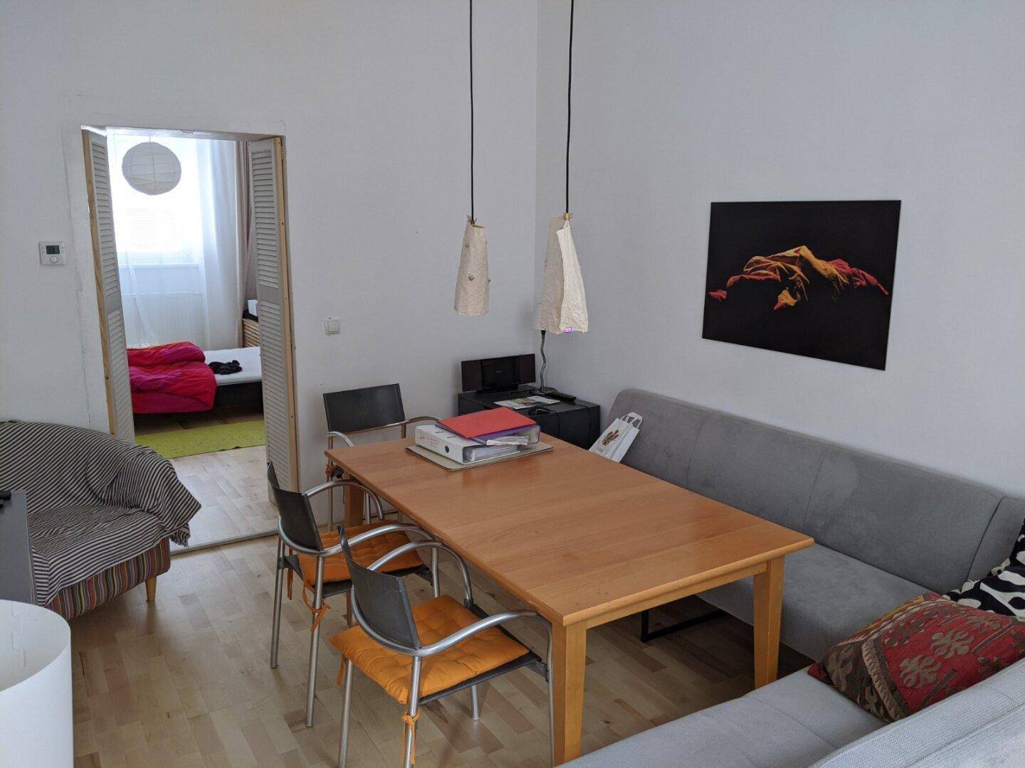 Essbereich mit Holztisch, Sitzbank und Blick in ein angrenzendes Zimmer.