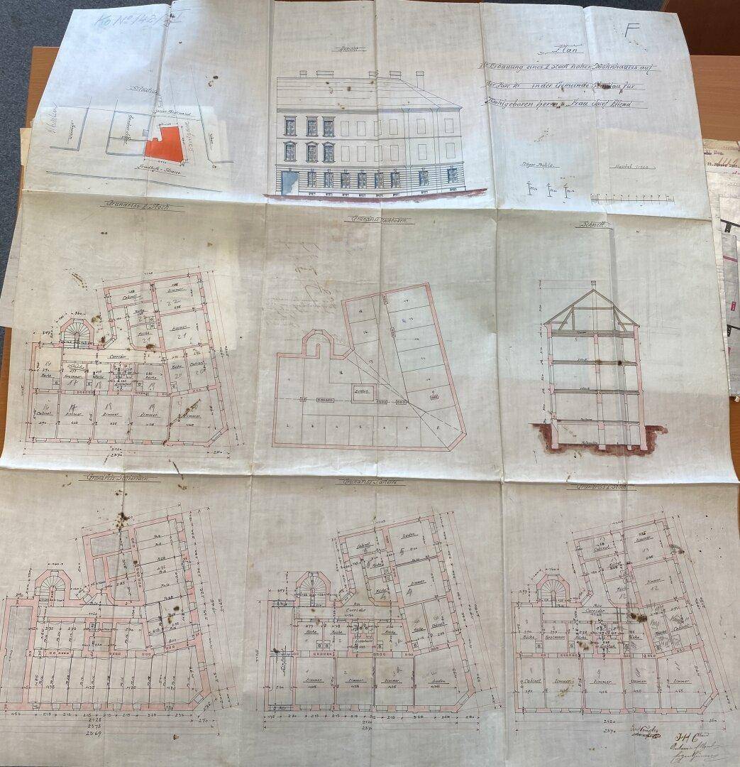 Historische Baupläne mit verschiedenen Grundrissen, Ansichten und einem Gebäudeschnitt auf gefaltetem Papier.