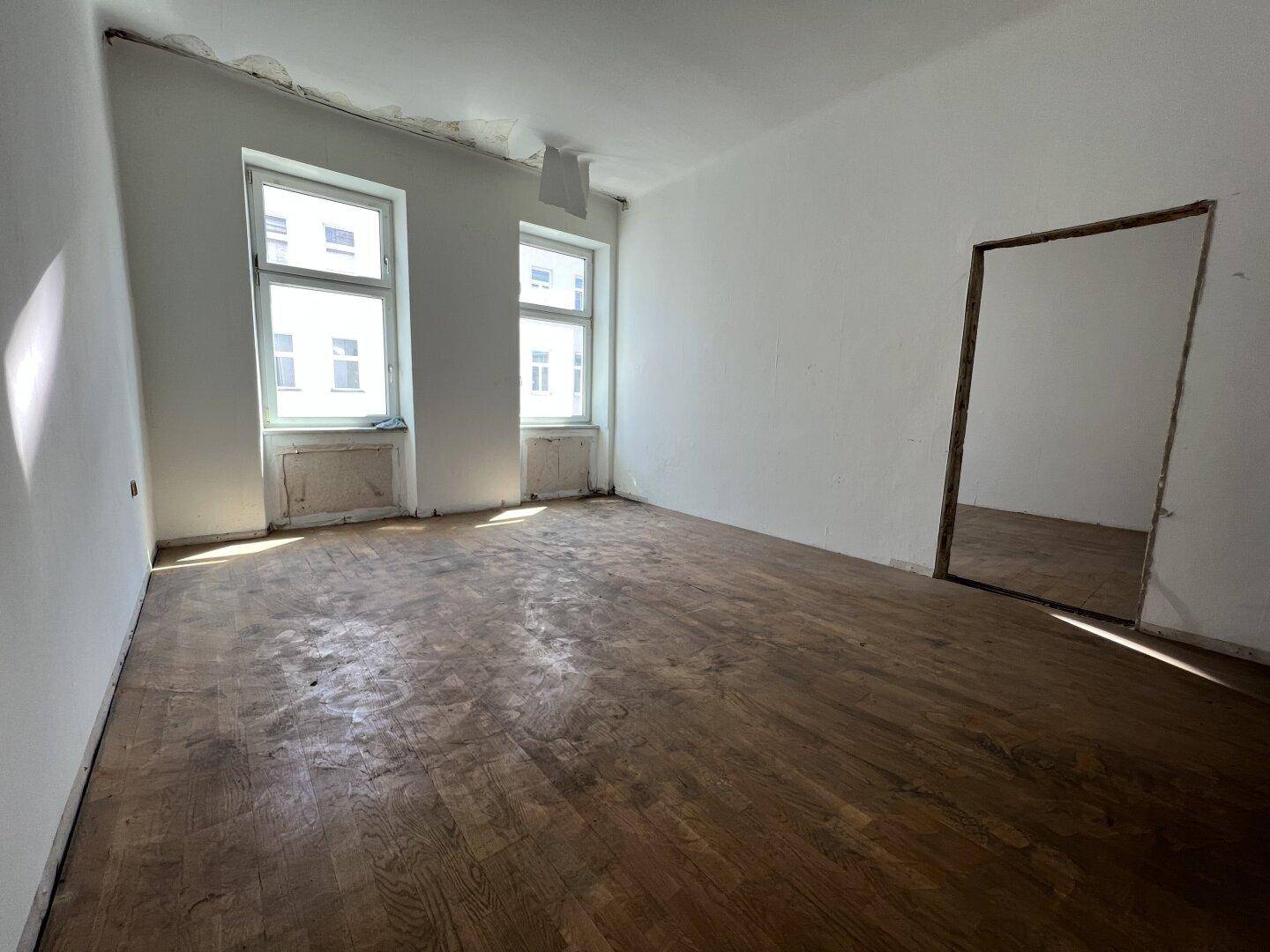 Geräumiger Raum mit Fischgrätparkett und zwei Fenstern, ideal für eine Neugestaltung.