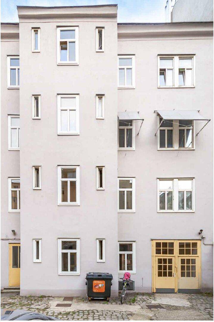 Rückfassade eines Gebäudes mit vielen Fenstern und einem Hinterhofbereich.