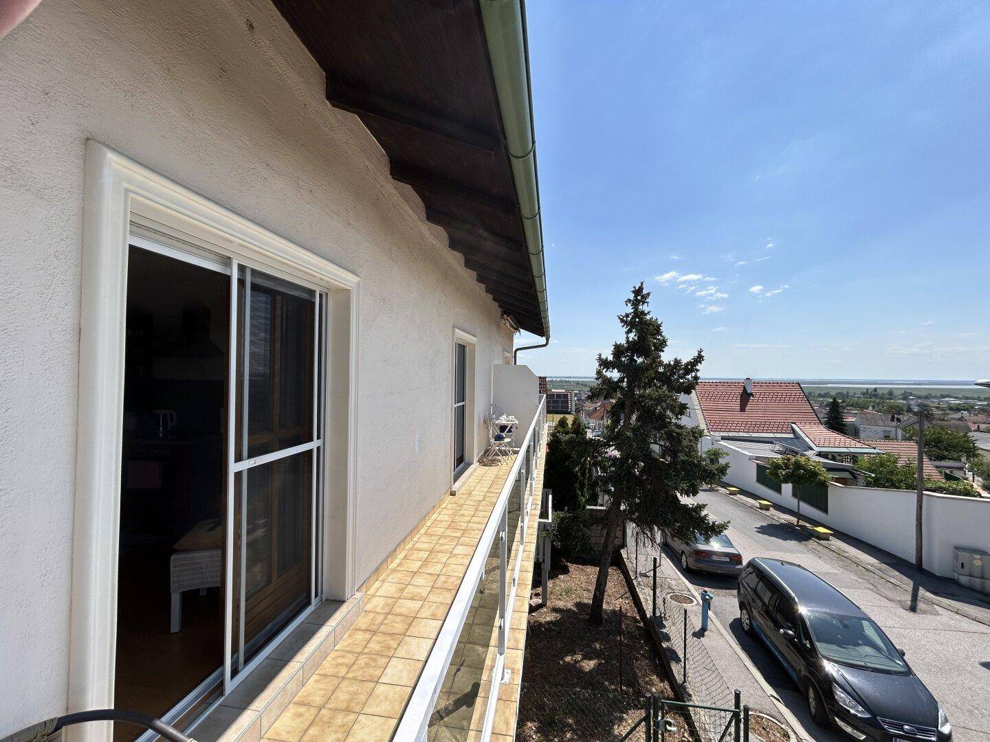 Geräumiger Balkon mit Fliesenboden und weitem Blick über die Nachbarschaft und Landschaft.