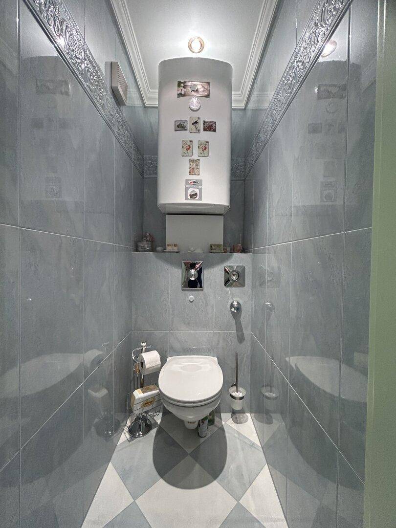 Kleines Gäste-WC mit blauen Fliesen und einem Wand-WC, funktional und sauber.