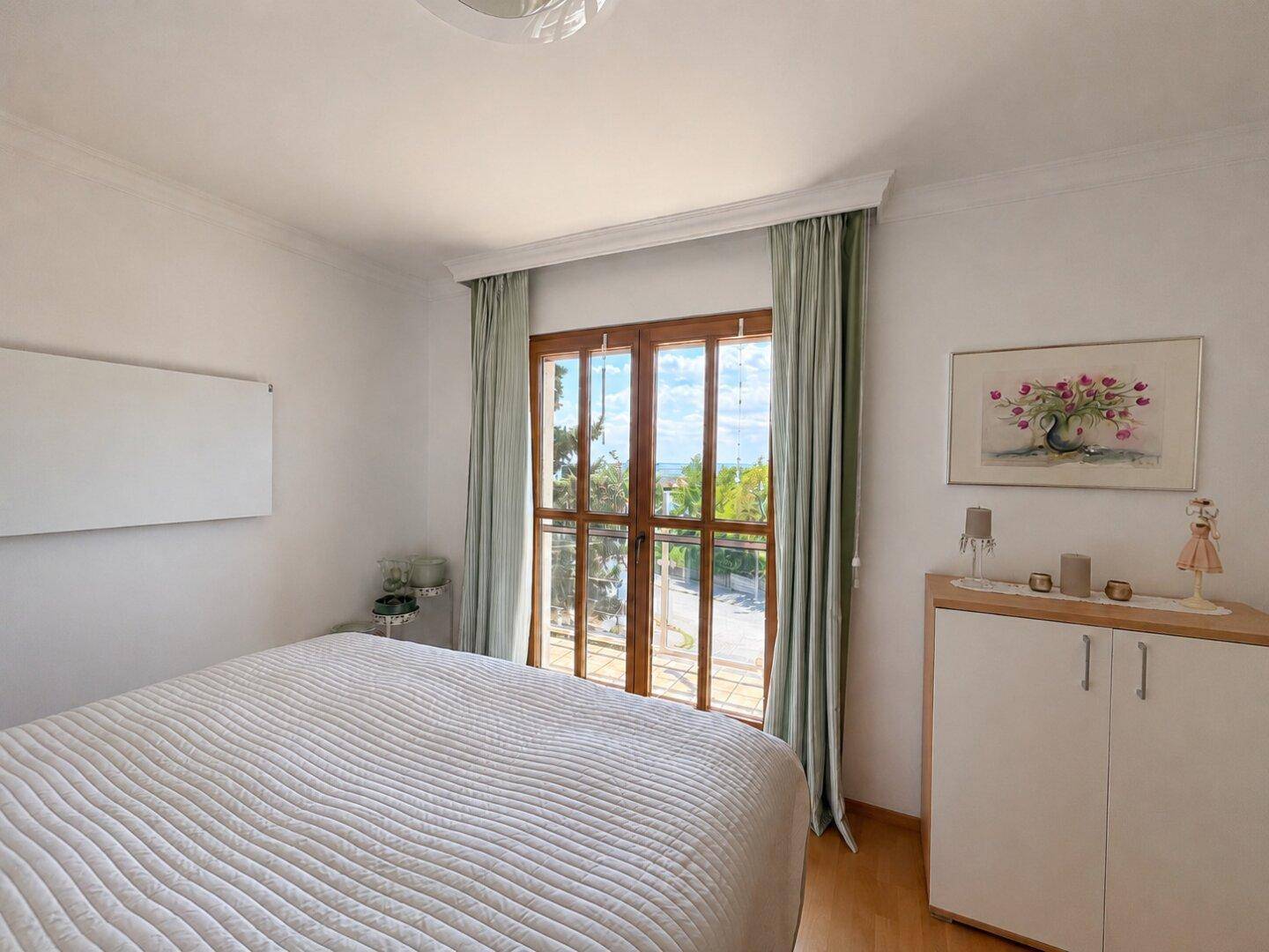 Helles Schlafzimmer mit Doppelbett und Zugang zu einem Balkon, der viel Licht hereinlässt.