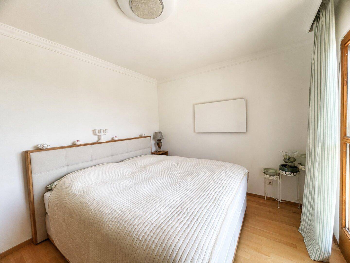Geräumiges Schlafzimmer mit großem Bett und hellem Holzboden, ideal für erholsame Nächte.