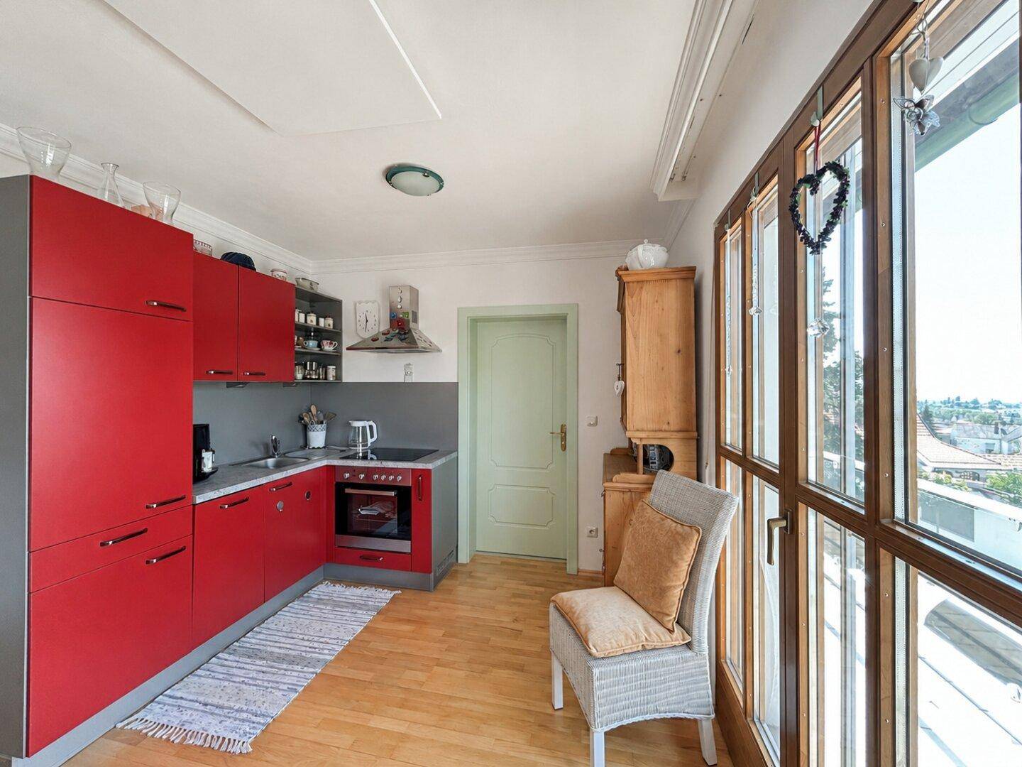 Funktionale Küche mit roten Schränken, integriertem Backofen und hellem Holzboden.