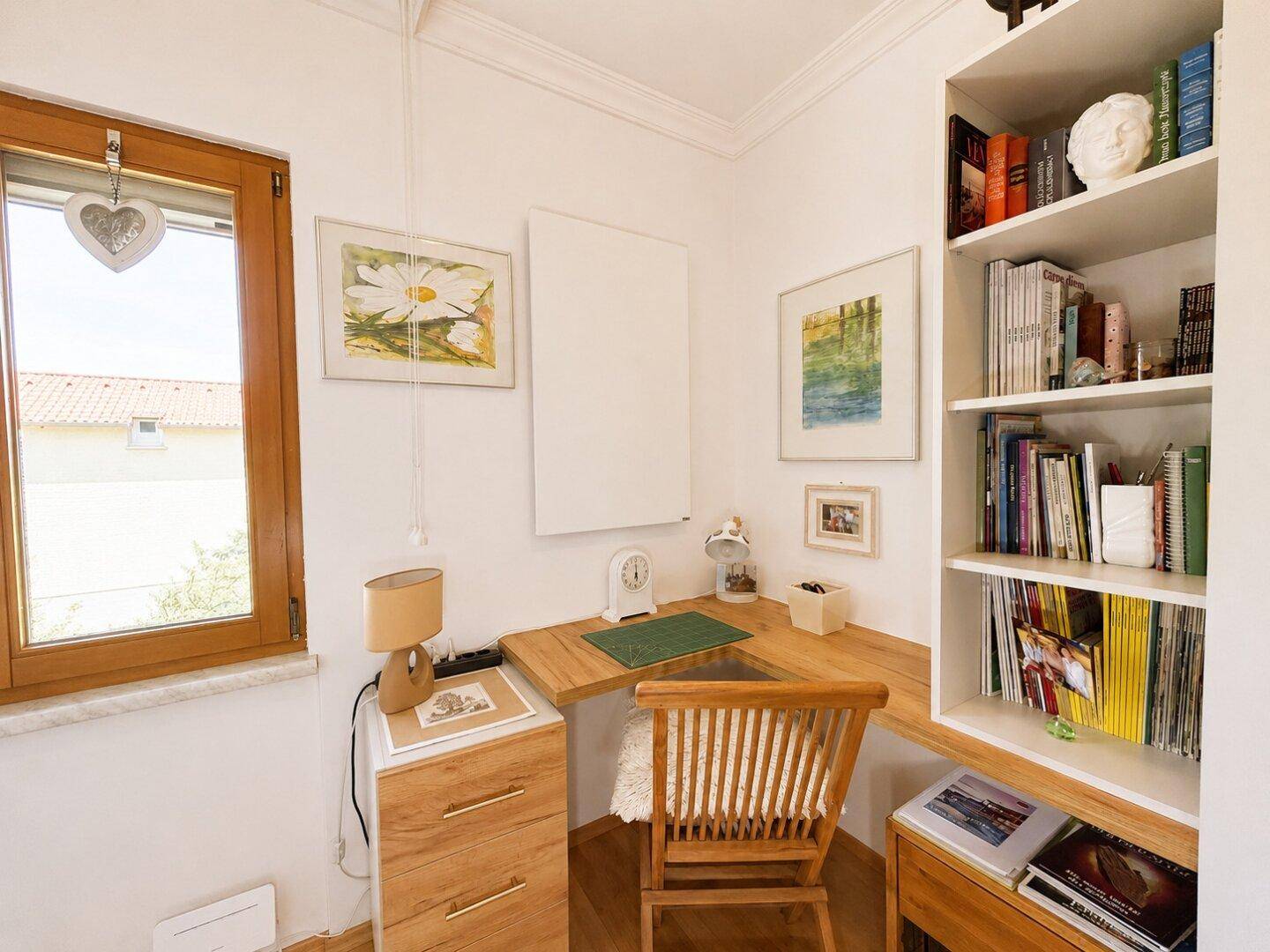 Heller Arbeitsbereich mit Eckschreibtisch, Bücherregal und Fenster für natürliches Licht.