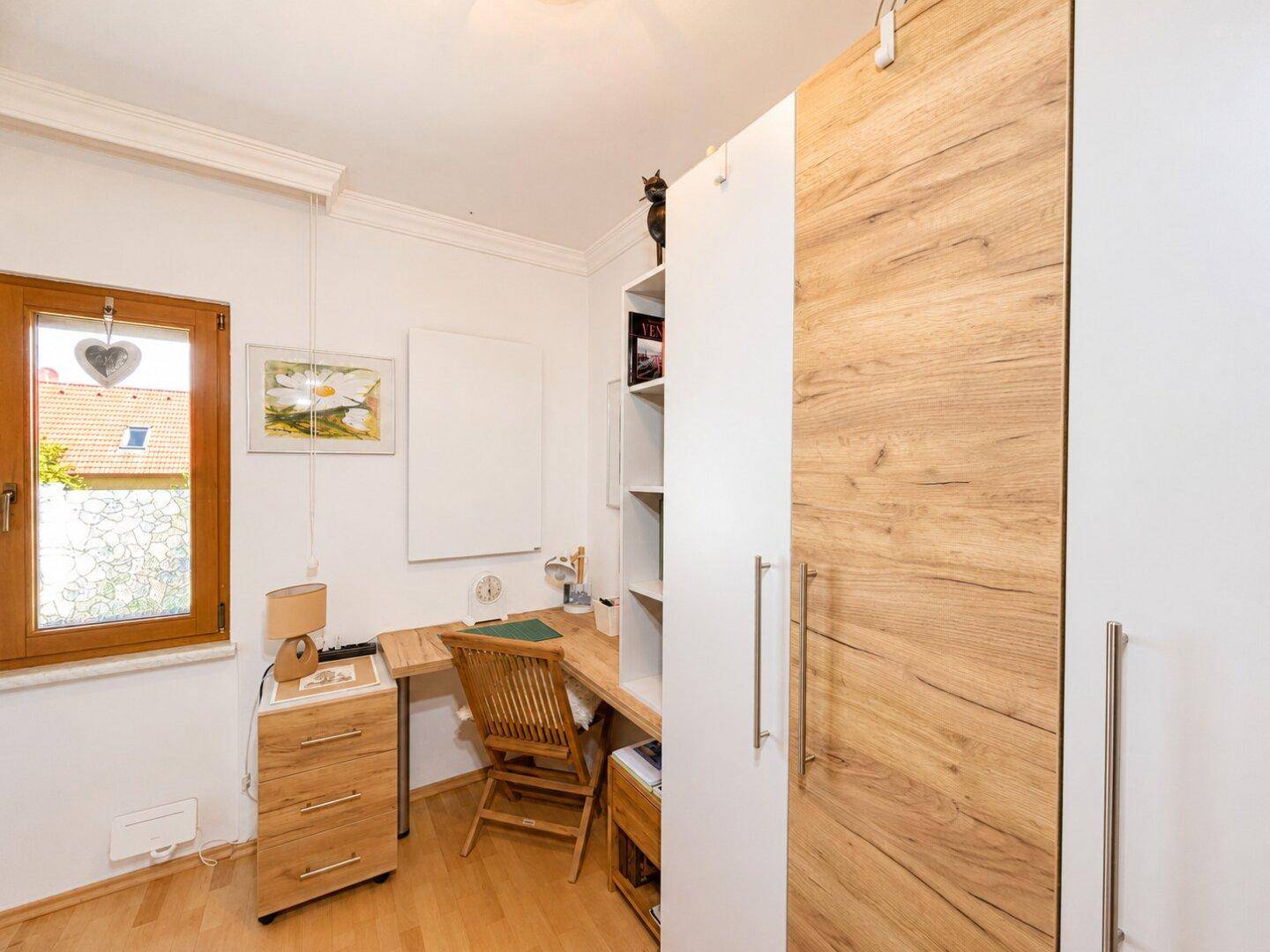 Arbeitszimmer mit Schreibtisch, Bücherregal und großem Schrank, hell und funktional.