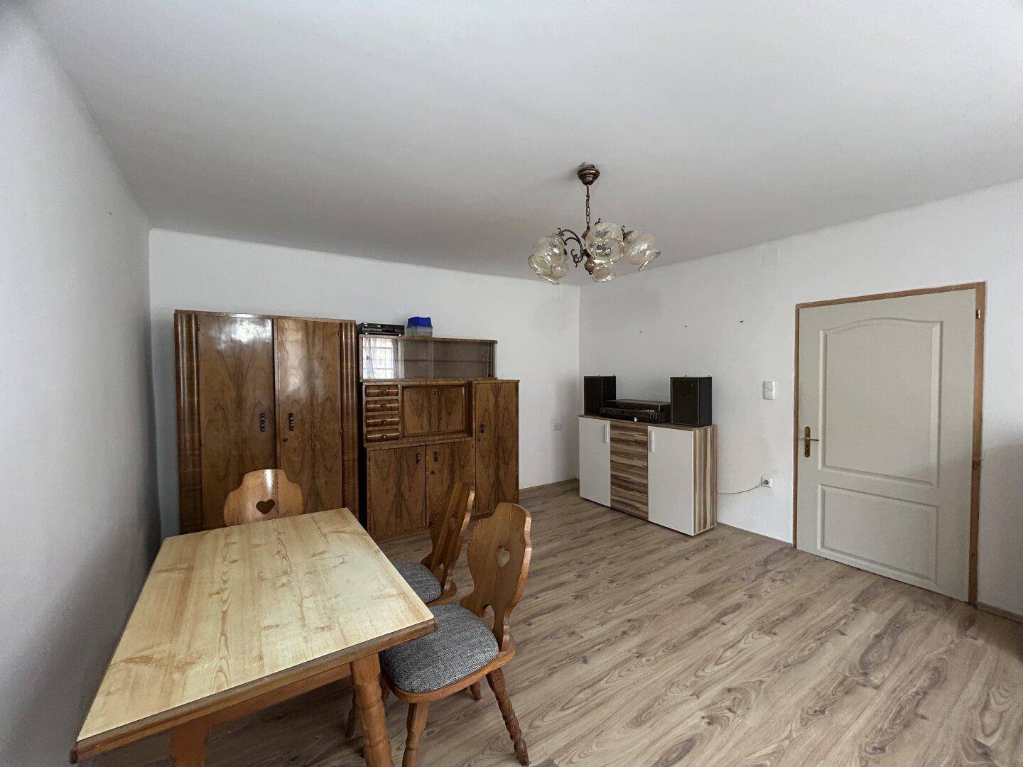 Esszimmer mit Laminatboden, Holztisch, Stühlen und traditionellen Holzschränken.