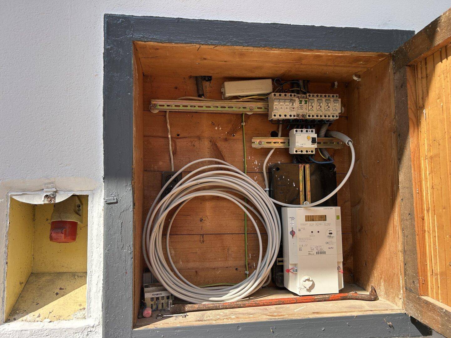 Offener Elektroschrank mit Zähler und Sicherungen an der Außenwand des Hauses.
