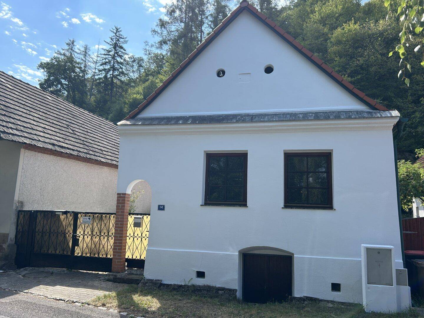 Vorderansicht des frisch gestrichenen Hauses mit rotem Ziegeldach und zwei Fenstern im Erdgeschoss.