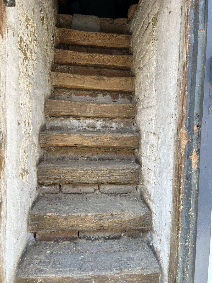 Rustikale Holztreppe führt in einen unteren Bereich, möglicherweise zum Keller.