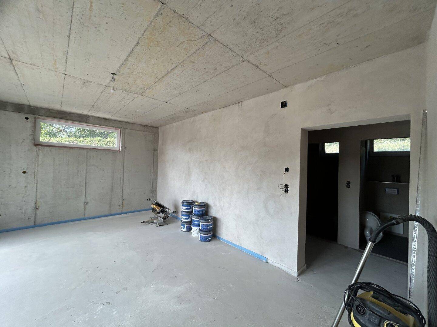 Unfertiger Raum mit Betonwänden und -decke, bereit für den weiteren Ausbau.