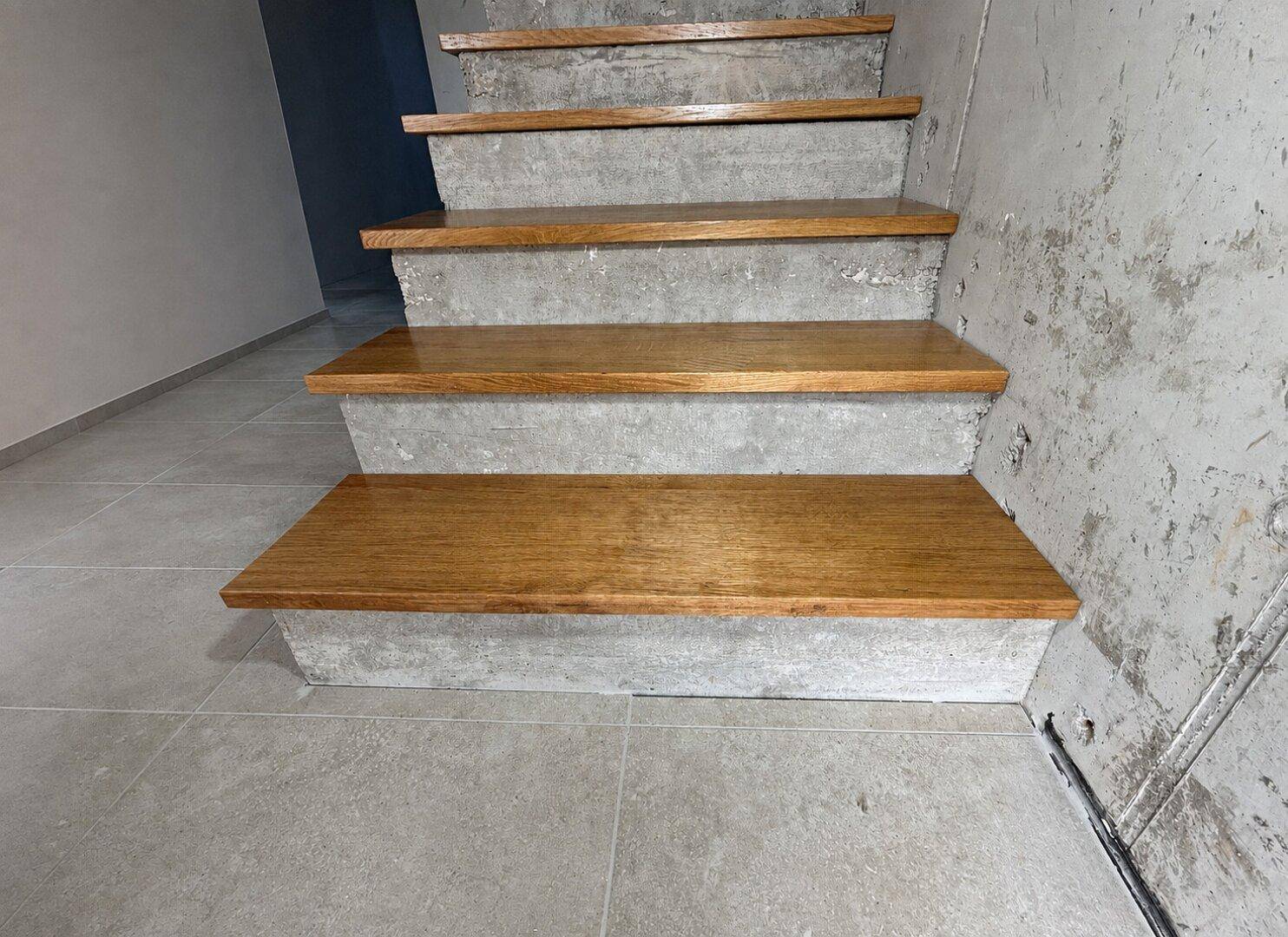 Treppe mit Holzstufen und Betonstruktur, führt zu den oberen Etagen.