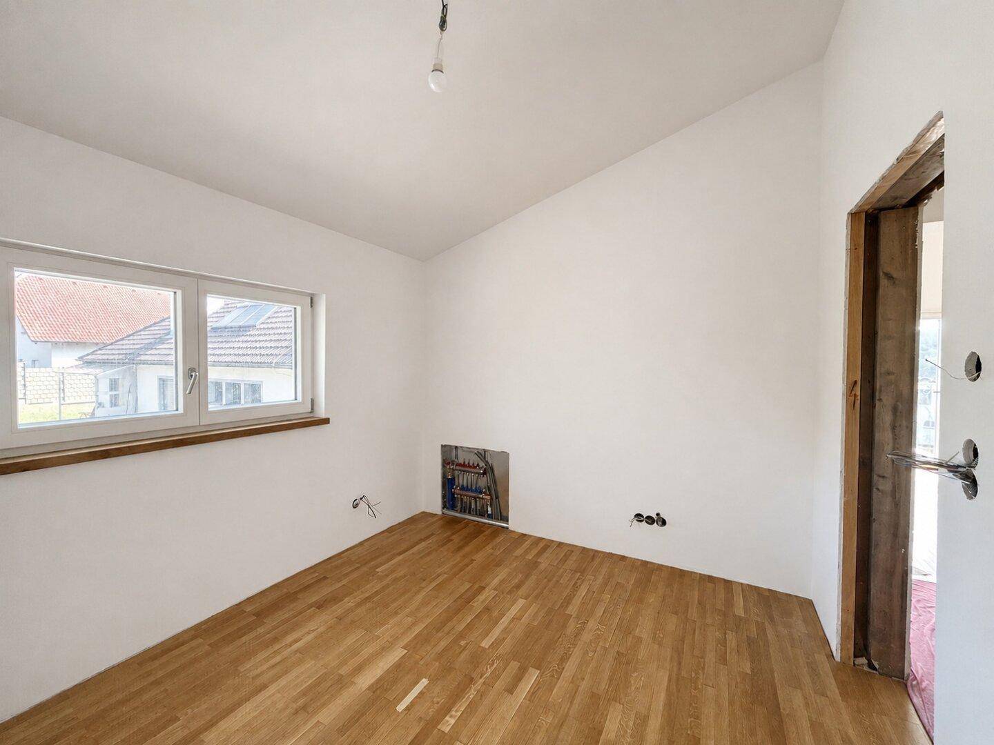 Helles Zimmer mit Parkettboden und Fenster, ideal als Schlaf- oder Arbeitszimmer.