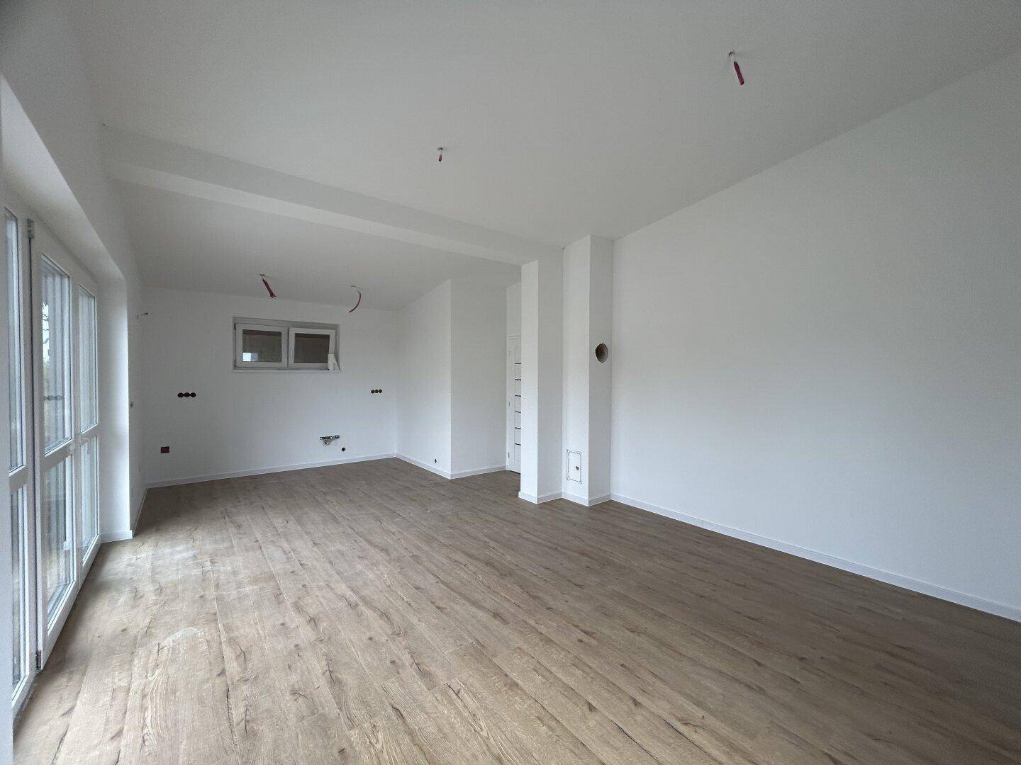 Weitläufiger Wohnbereich mit hellem Laminatboden und viel Potenzial für individuelle Einrichtungsideen.