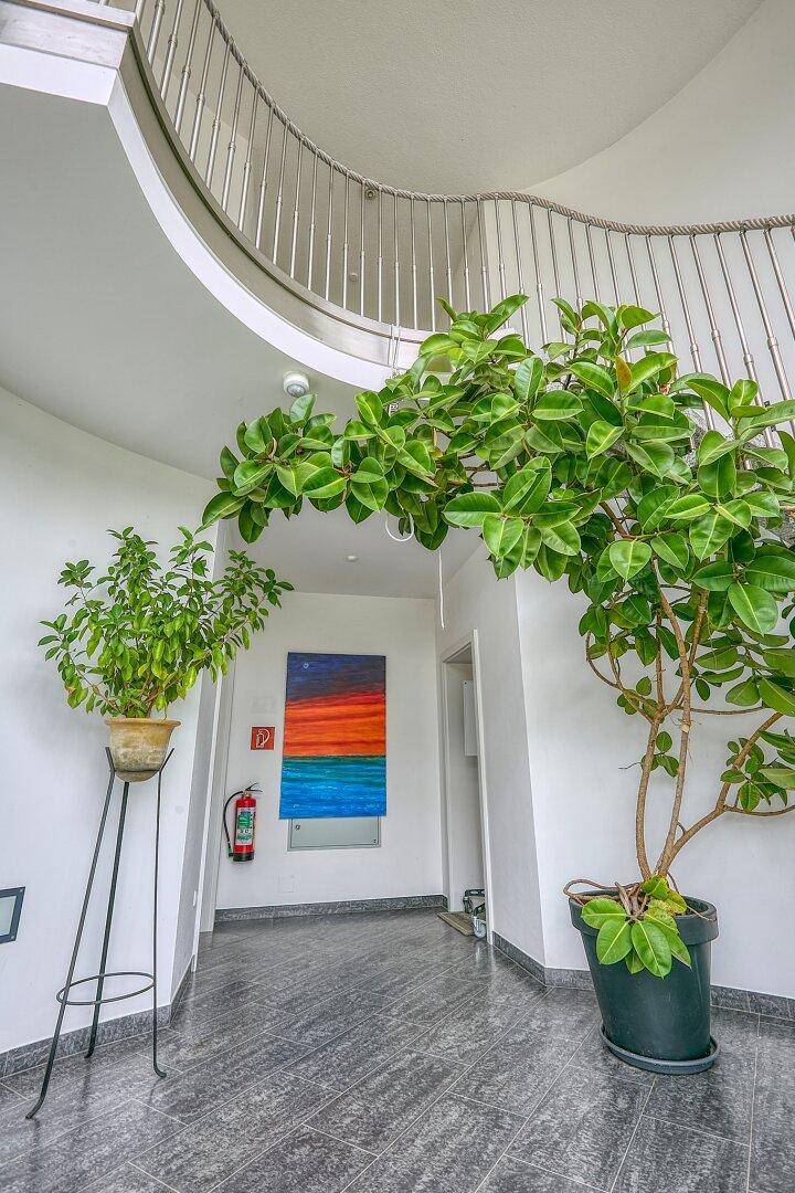 Moderner Flur mit Fliesenboden, Kunst an der Wand und Blick zur oberen Etage.