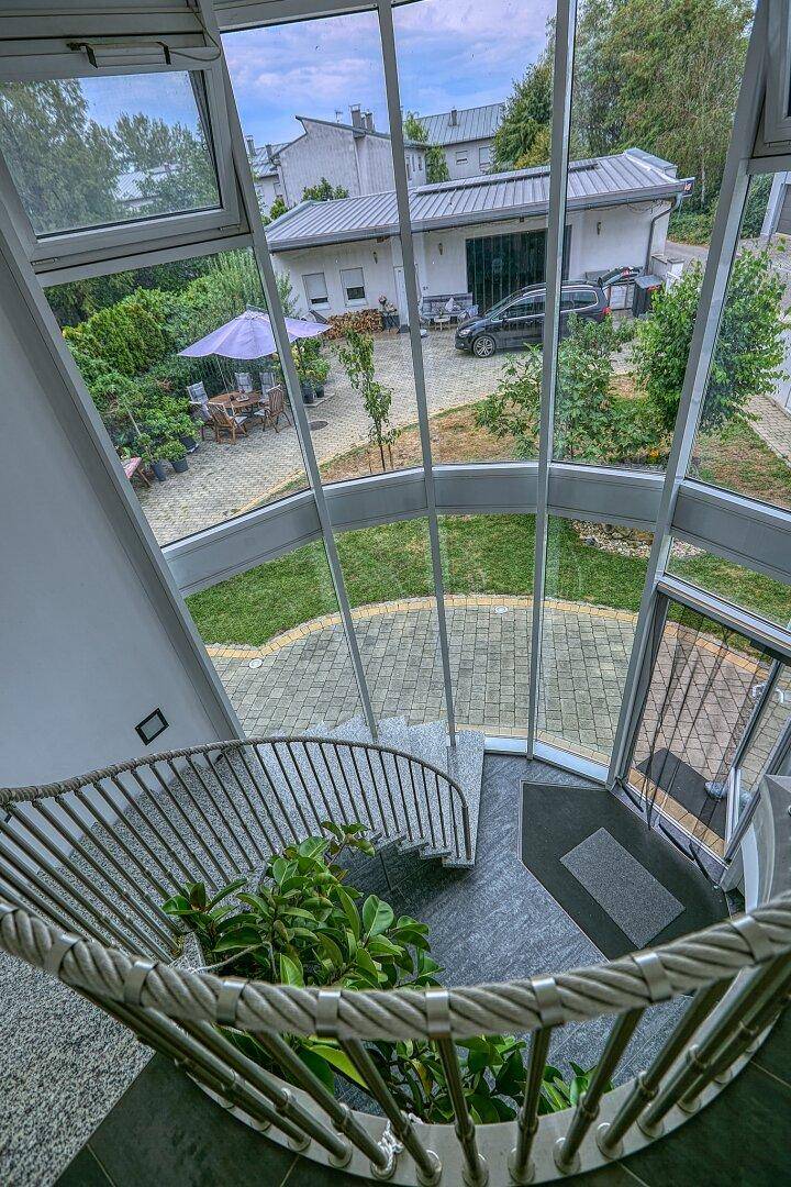Blick von der Wendeltreppe auf den gepflegten Garten mit Terrasse und Sitzbereich.