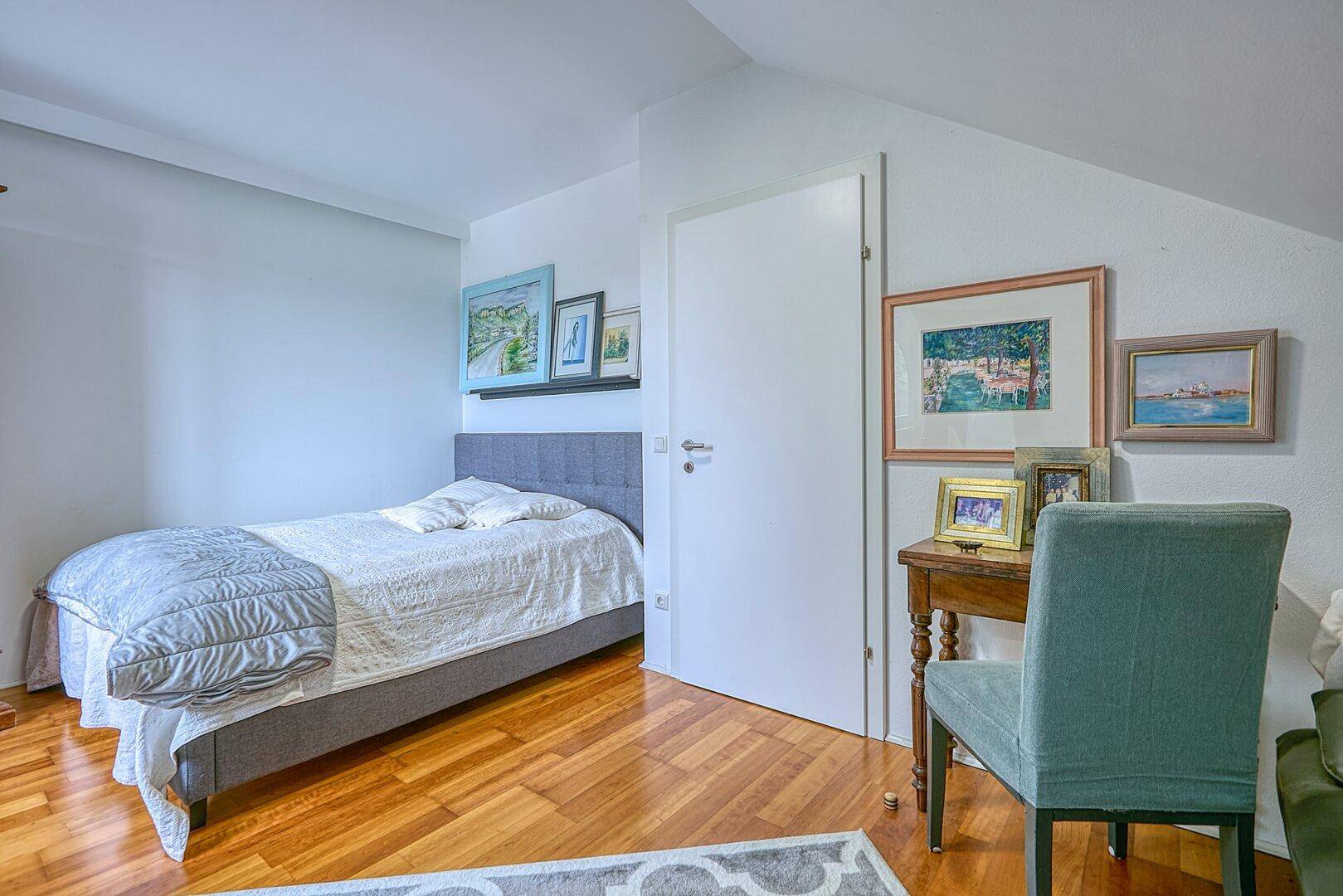 Helles Dachzimmer mit Einzelbett, Schreibtisch und Holzboden.