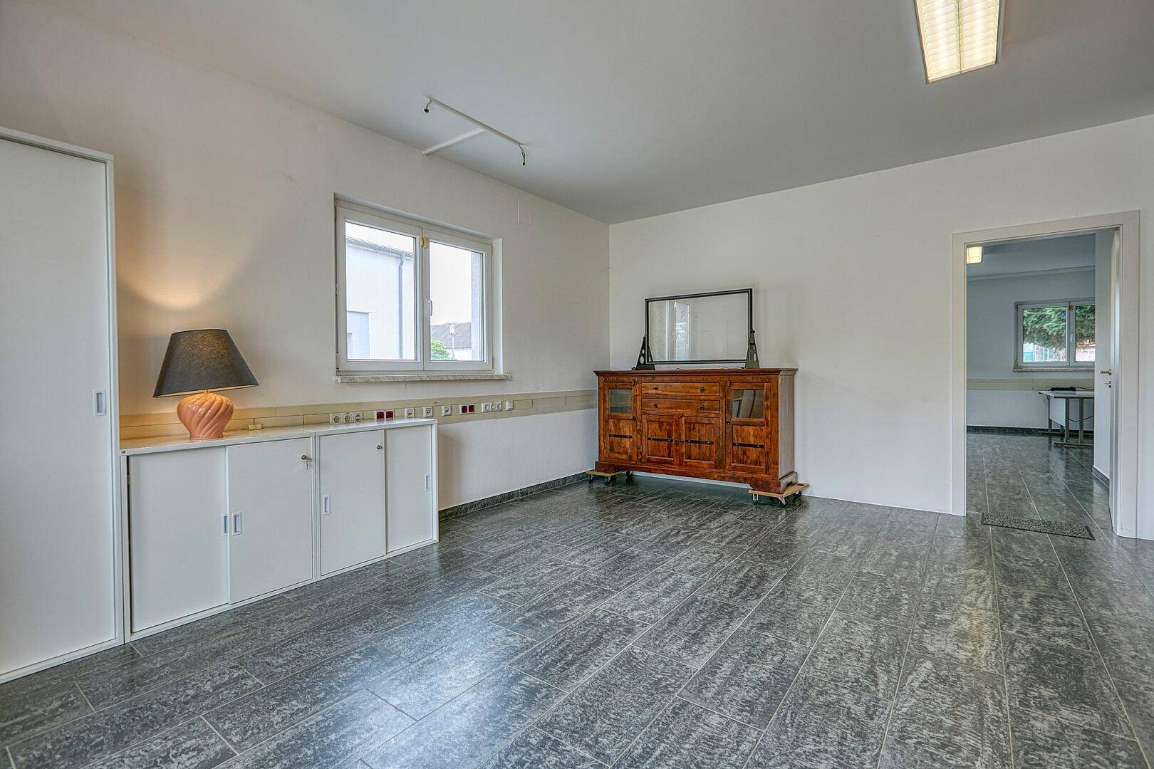 Heller Raum mit weißen Schränken, einem Holzschrank und Blick nach draußen.