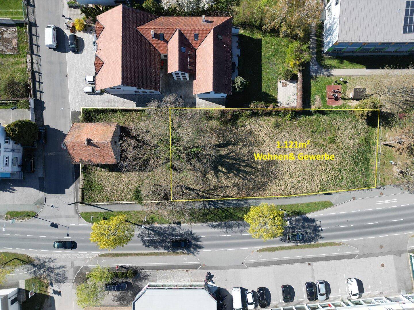 Luftaufnahme eines Baugrundstücks mit umliegenden Gebäuden und Straßen in einer ländlichen Umgebung.