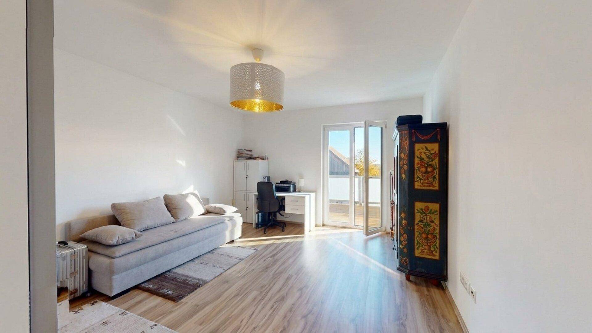 Helles Arbeitszimmer mit Sofa, Schreibtisch und Zugang zu einem Balkon, ideal für Home-Office.