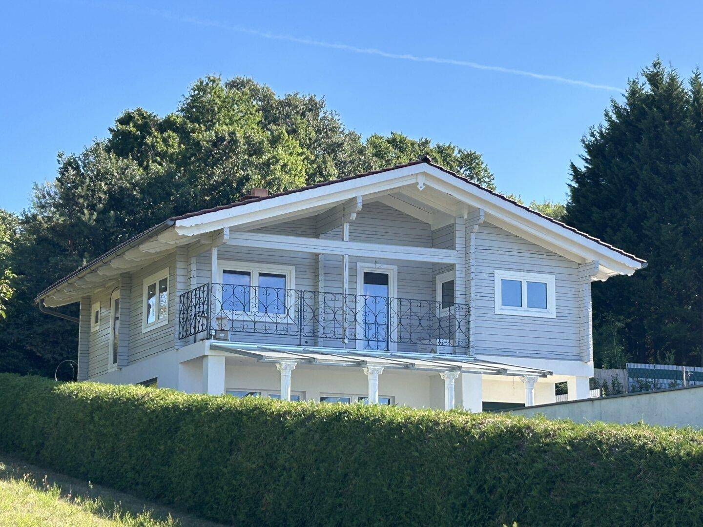 Seitenansicht des modernen Hauses mit Balkon und Blick auf die umliegende Natur.