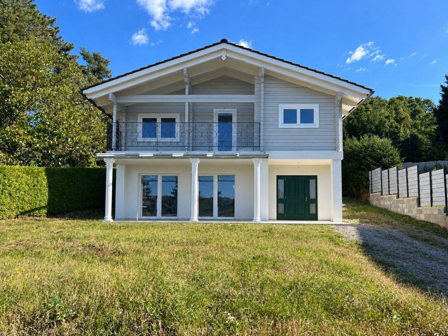 Freistehendes Einfamilienhaus mit Balkon, überdachter Terrasse und großem Gartenbereich.