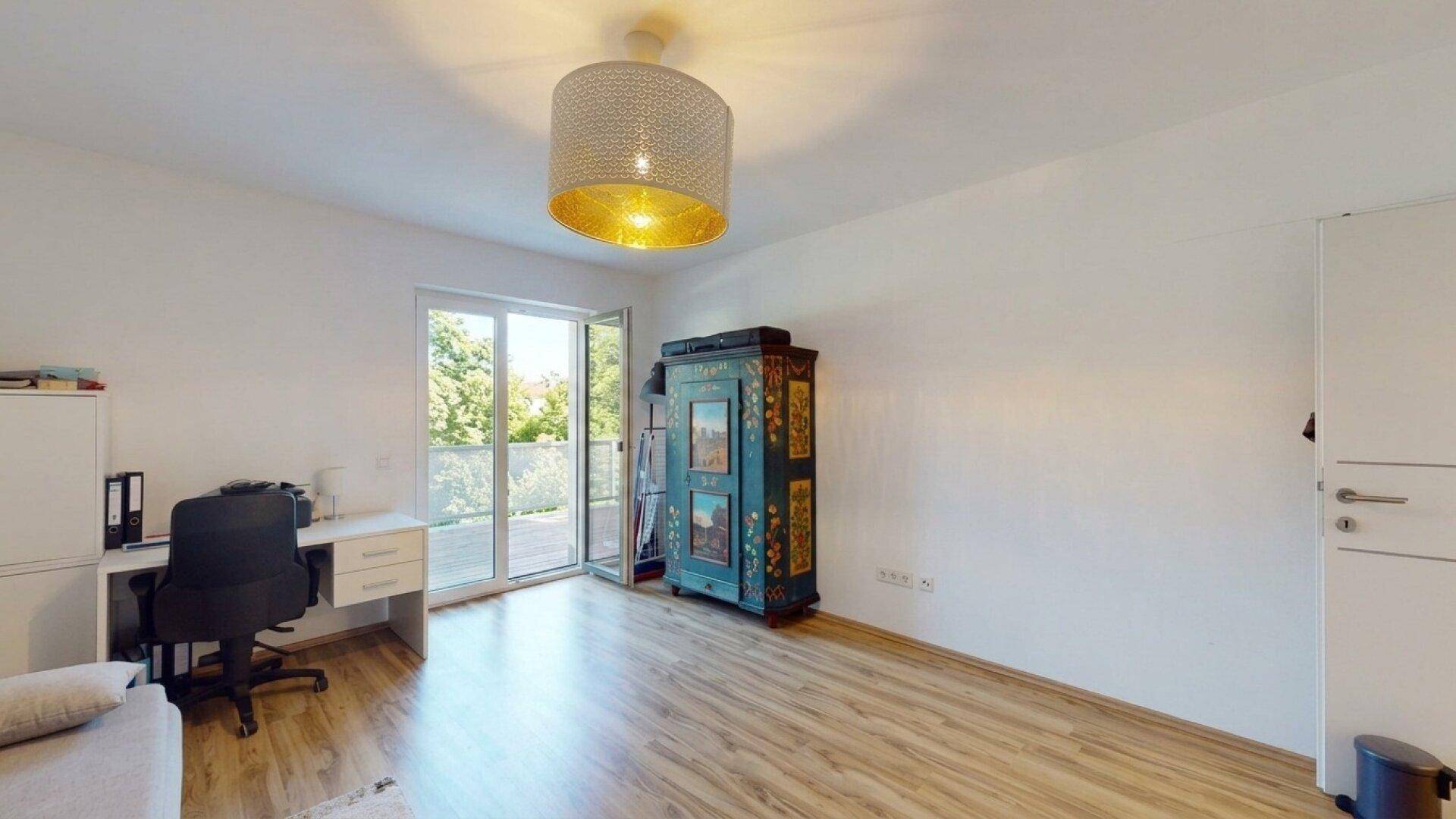 Geräumiges Arbeitszimmer mit Schreibtisch, farbenfrohem Schrank und direktem Zugang zum Balkon.