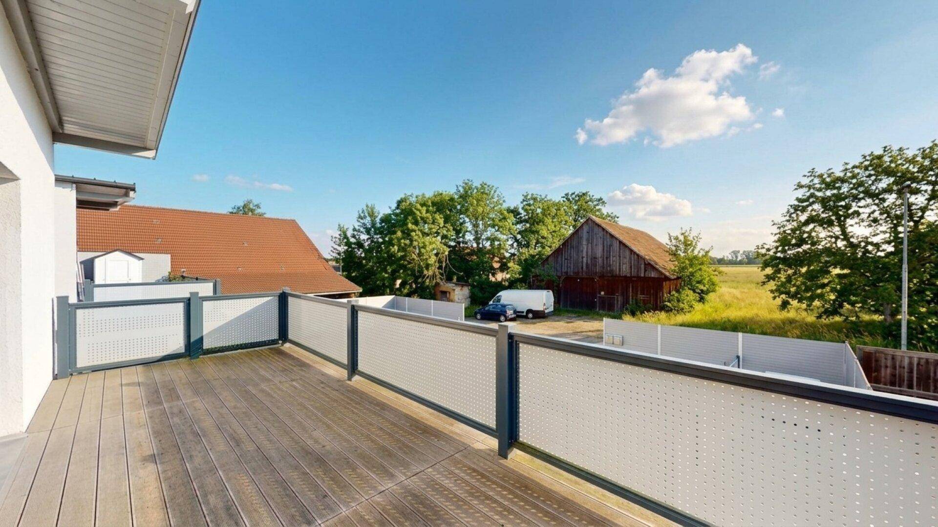 Großer Balkon mit Holzboden und weitem Blick über die umliegende Landschaft.