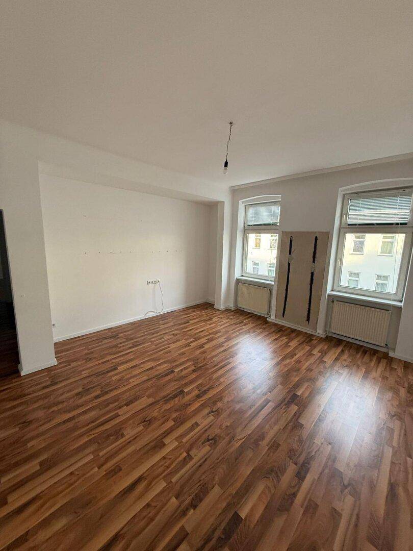 Großes, helles Zimmer mit Laminatboden und zwei Fenstern, bietet viel Platz für Wohnideen.