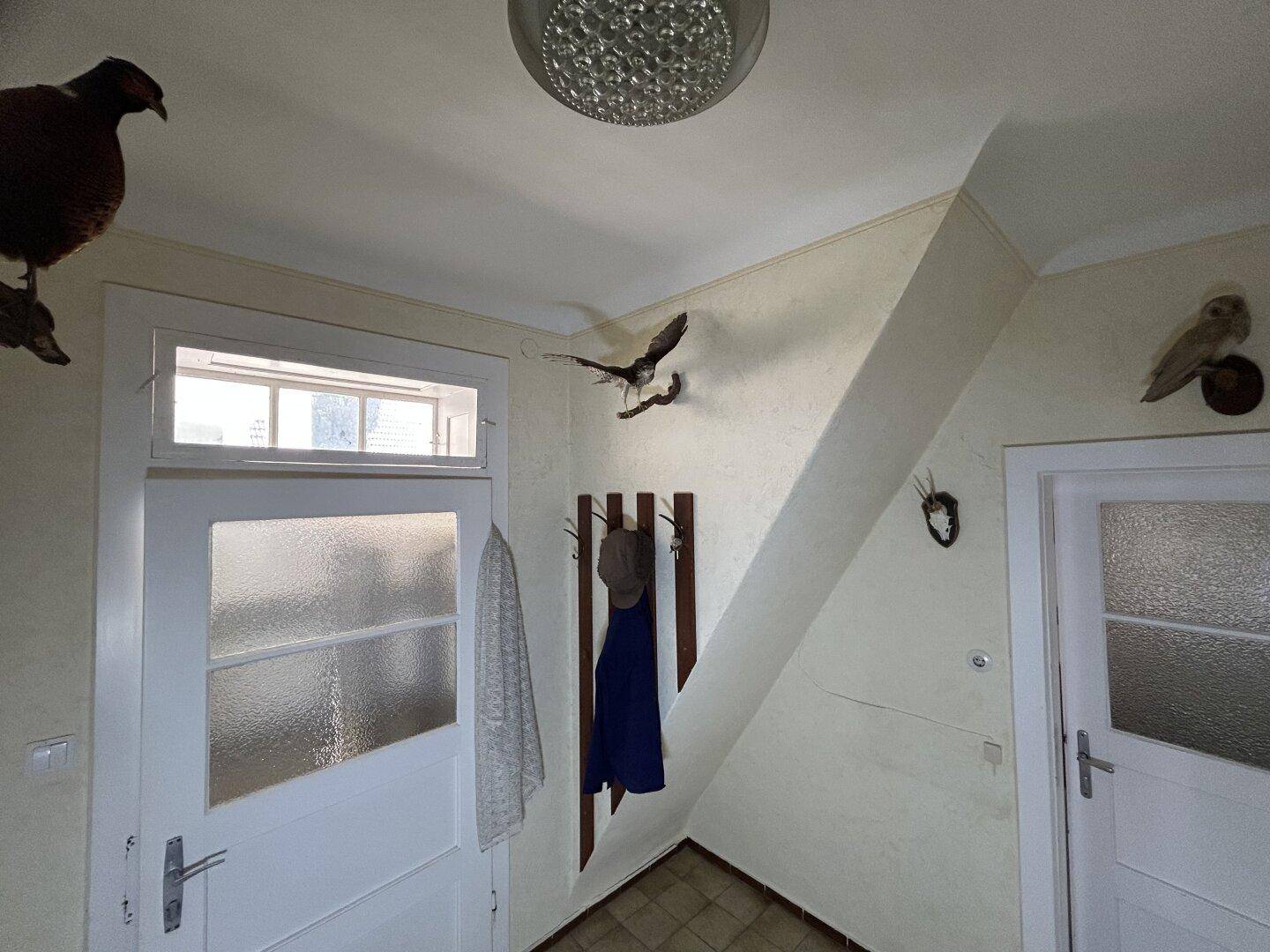 Heller Flur mit Garderobe, Fliesenboden und traditioneller Dekoration an den Wänden.