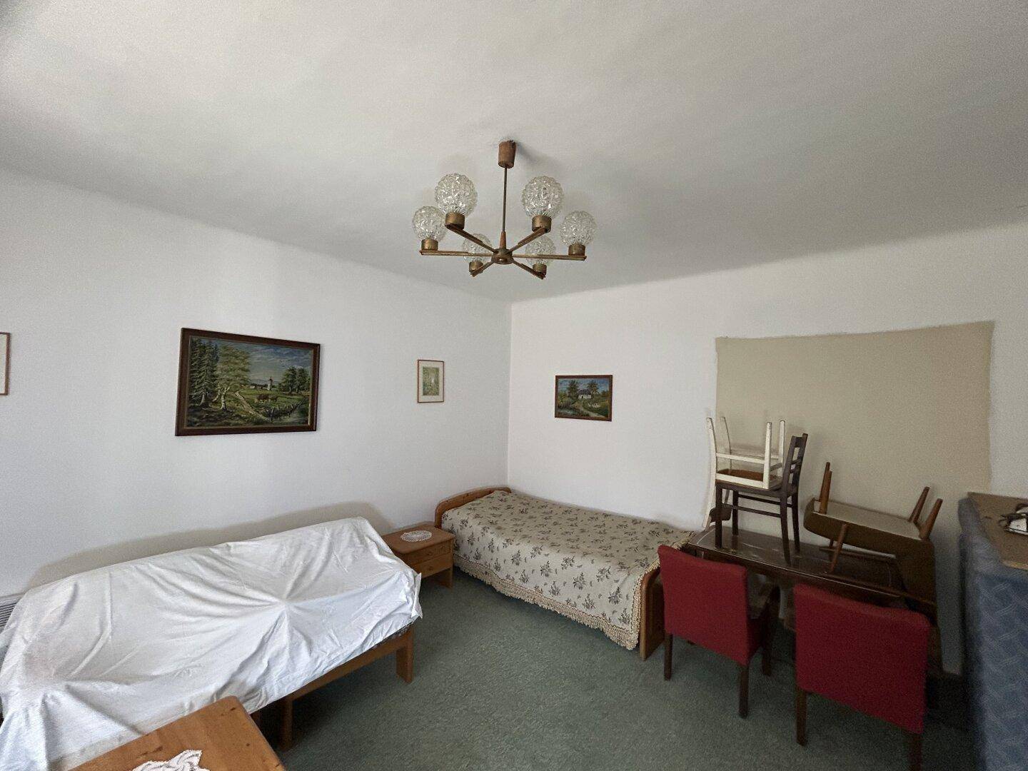 Schlafzimmer mit zwei Einzelbetten, Teppichboden und einem Kronleuchter an der Decke.