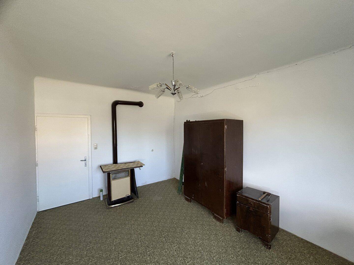 Schlafzimmer mit Teppichboden, einem Kleiderschrank und einem traditionellen Holzofen.
