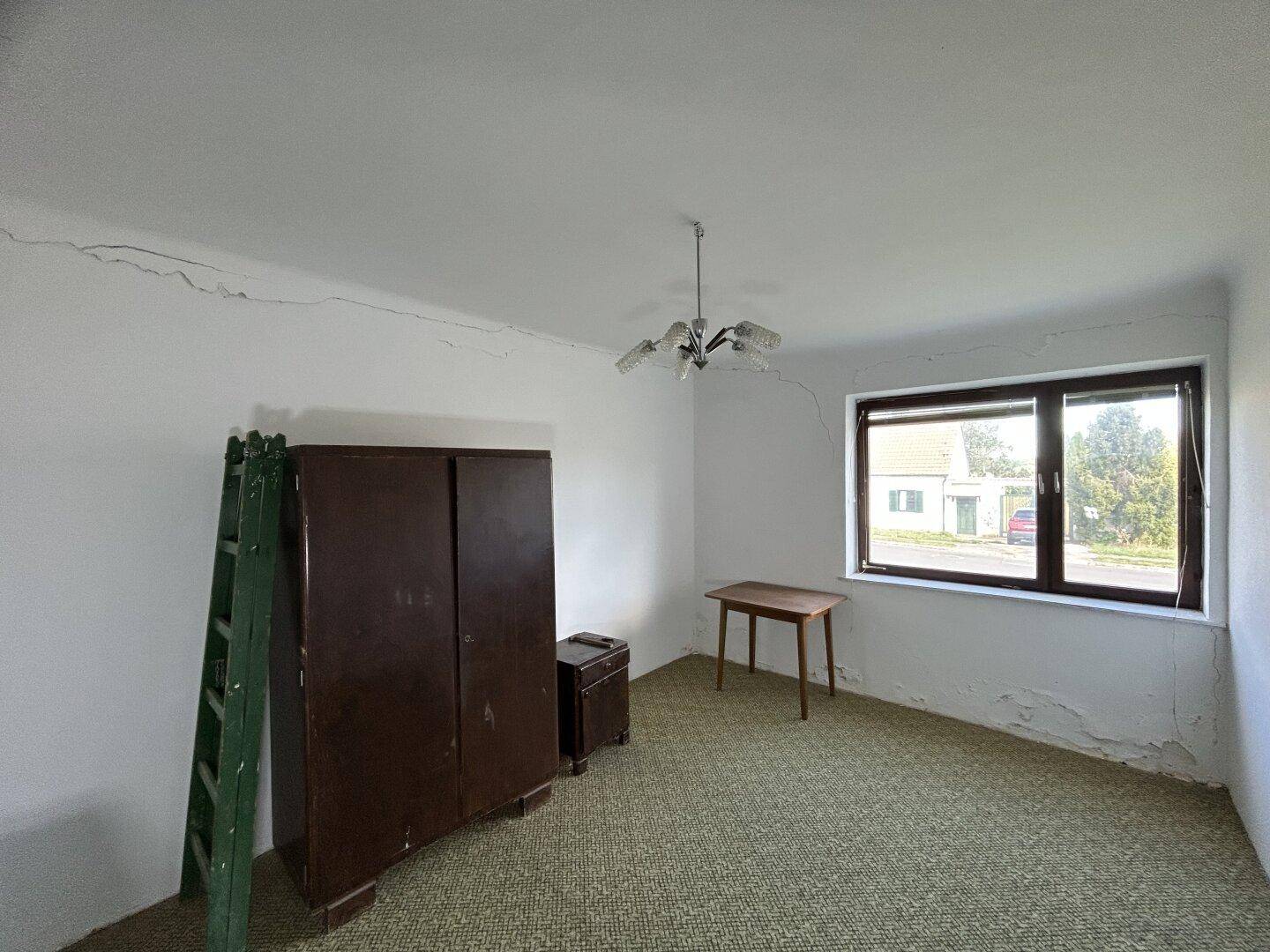Schlafzimmer mit Teppichboden, Kleiderschrank und einem Fenster mit Blick nach draußen.